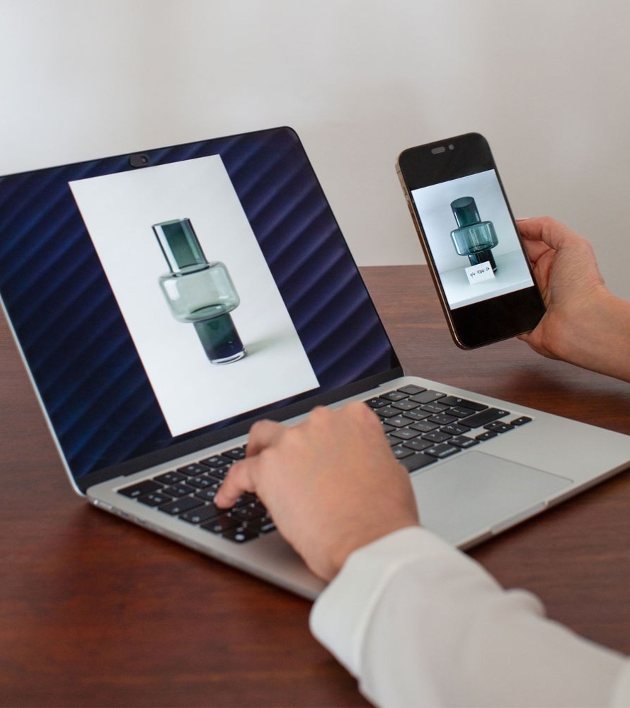 A person comparing a product image on a laptop and smartphone during digital image development.