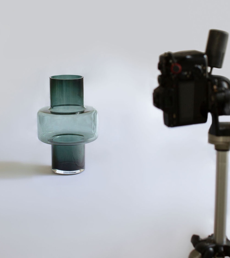 A glass vase positioned in front of a professional camera for studio photography.